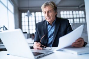 A man on his Navy-blue suit while looking at his laptop